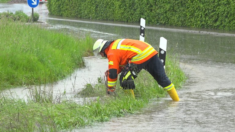 Ein Feuerwehrmann steht auf einer überschwemmten Straße. (Foto: Kamera24)