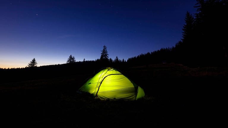 Ein beleuchtetes Zelt bei Nacht im Schwarzwald