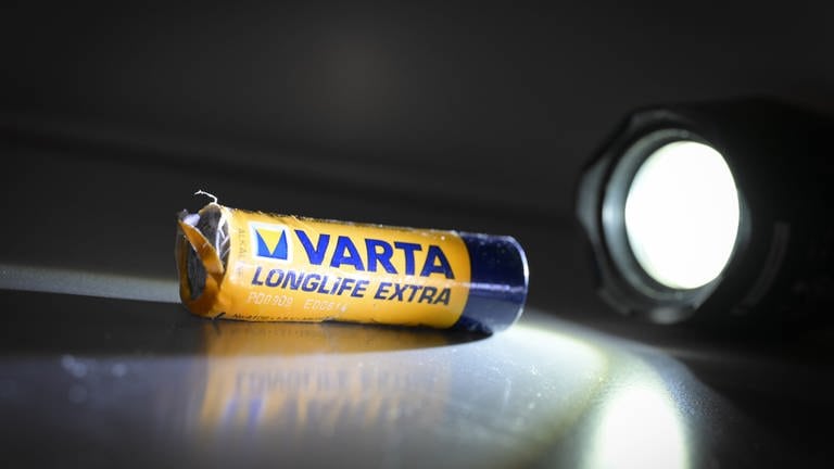 Eine kaputte Varta-Batterie wird von einer Taschenlampe angeleuchtet. Varta-Chef Markus Hackstein soll kurz nach der Veröffentlichung schlechter Nachrichten für sein Unternehmen Aktien verkauft haben - noch bevor der Kurs abstürzte. (Foto: dpa Bildfunk, picture alliance/dpa | Felix Kästle)