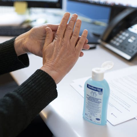 Ein Arbeitnehmer desinfiziert sich im Büro die Hände (Foto: dpa Bildfunk, picture alliance/dpa/KEYSTONE | Christian Beutler)