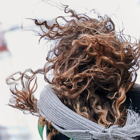 Eine Frau mit Schal um den Hals und im Wind wehenden Haaren bewegt sich im Freien (Foto: dpa Bildfunk, picture alliance/dpa | Annette Riedl)
