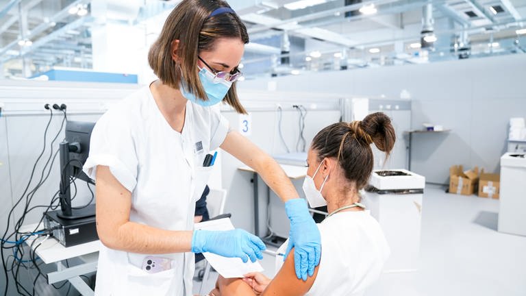 Eine Krankenschwester impft eine andere Krankenschwester