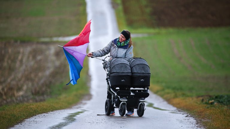 Eine Frau mit Kinderwagen versucht im stürmischen Wind ihren Regenschirm zu öffnen. (Foto: dpa Bildfunk, picture alliance/dpa | Thomas Warnack)