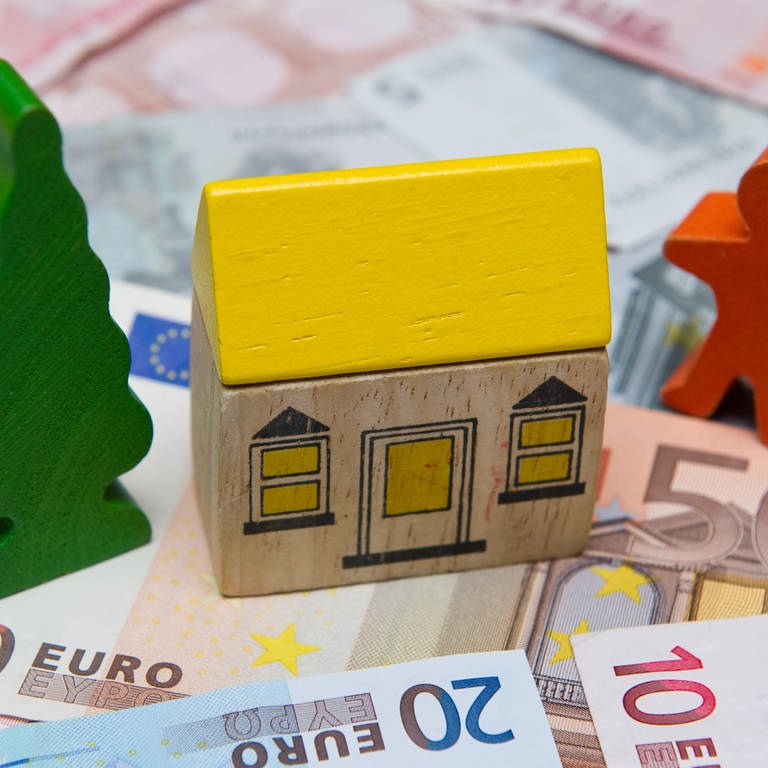 Ein kleines Spielzeughaus auf Geldscheinen (Sujet: Immobilien-Preisspiegel 2023) (Foto: dpa Bildfunk, Picture Alliance)
