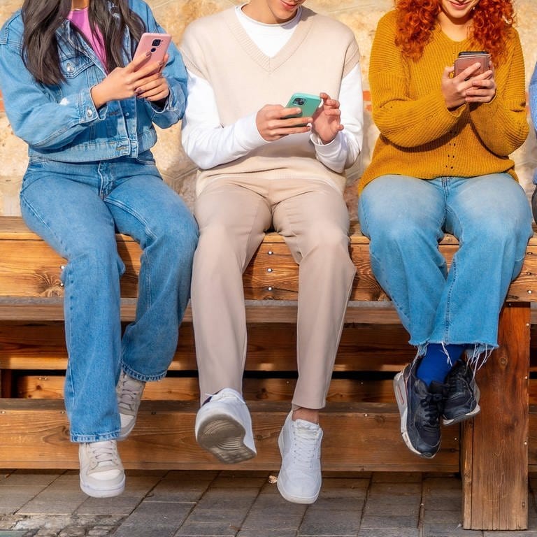 Eine Gruppe junger Menschen sitzt auf einer Bank (Foto: IMAGO, IMAGO / imagebroker)