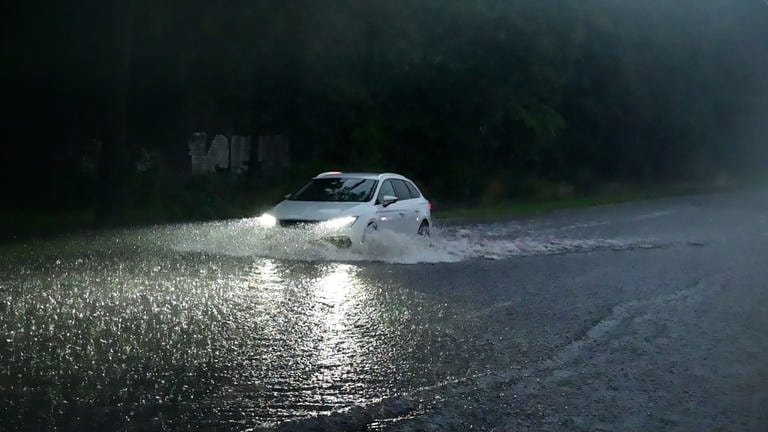 Drohendes Unwetter: Auto fährt über überflutete Straße