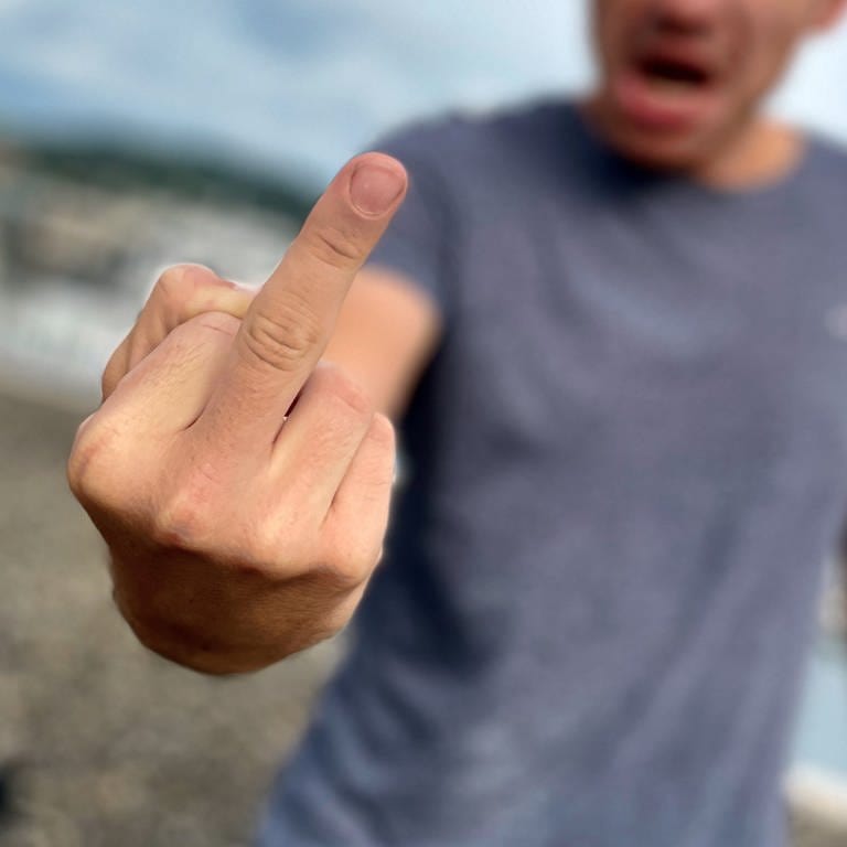Aggressiver Mann zeigt einen Mittelfinger in die Kamera. Hass und Beleidigungen sind inzwischen oft Alltag in Kliniken der Region Trier.