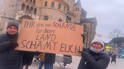 Menschen demonstrieren auf dem Trierer Domfreihof dagegen, dass die AfD in der Volkshochschule eine interne Parteiveranstaltung abhält.