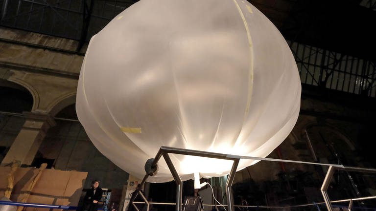 ein Ballon aus weißer Ballonseide schwebt in einer Fabrikhalle
