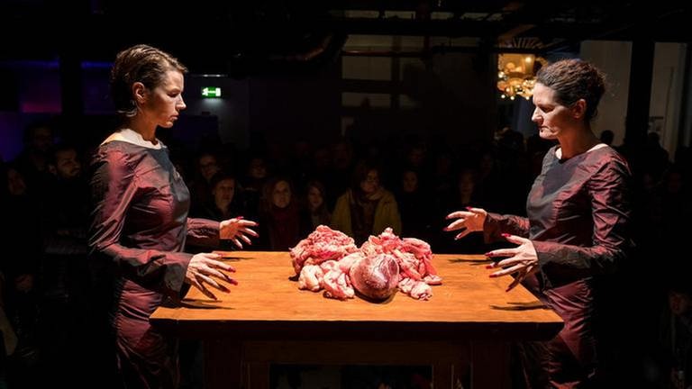 Zwei Frauen stehen an einem Tisch mit zwei rohen Rinderherzen