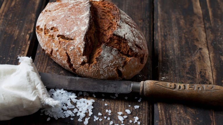 Laib Brot mit einem Messer und ein Säckchen mit Salz