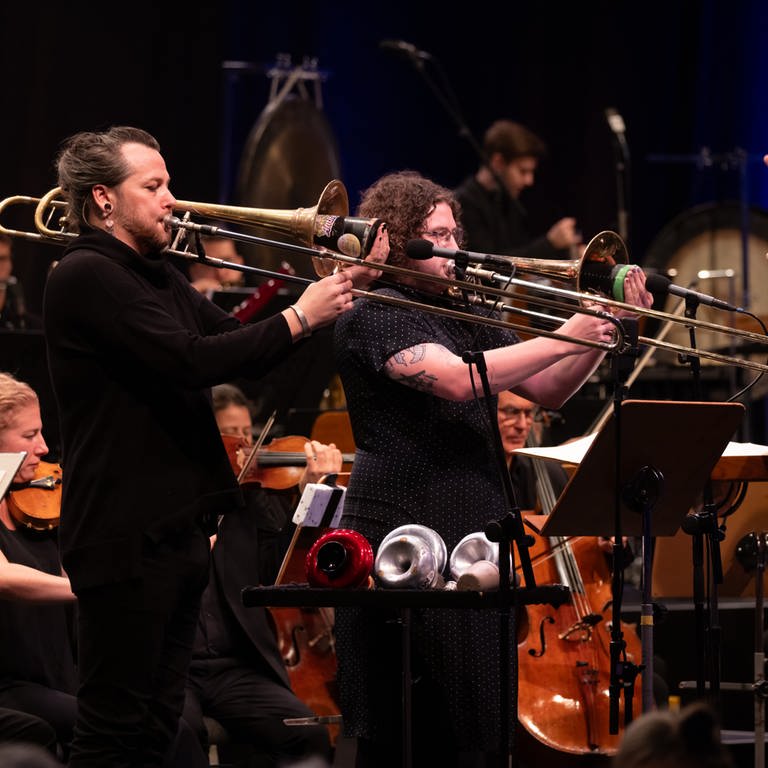 Konzertbild: Zwei Solo-Posaunisten, Dirigent und Orchester im Hintergrund (Foto: SWR, Ralf Brunner)