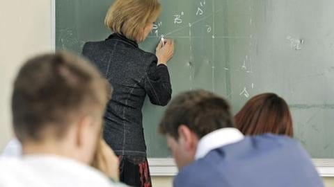 Eine Lehrerin rechnet etwas an der Tafel vor (Foto: Getty Images, Thinkstock -)
