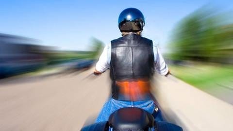 Motorradfahrer fährt mit hoher Geschwindigkeit. Die Umgebung drum herum verschwimmt durch die Bewegungsunschärfe. (Foto: Getty Images, Thinkstock -)