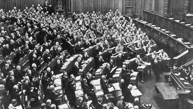 NSDAP und DNVP hatten den Reichstag verlassen. In Braunhemden kehren die Abgeordneten der NSDAP auf ihre Plätze zurück.