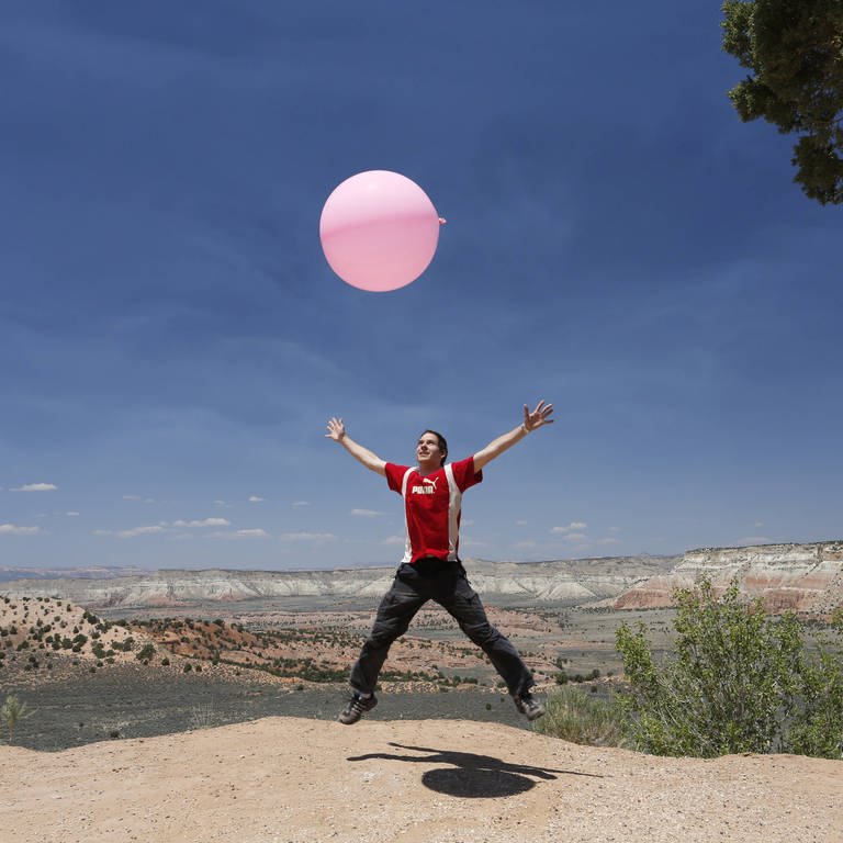 Mann springt in die Luft mit großem Ballon