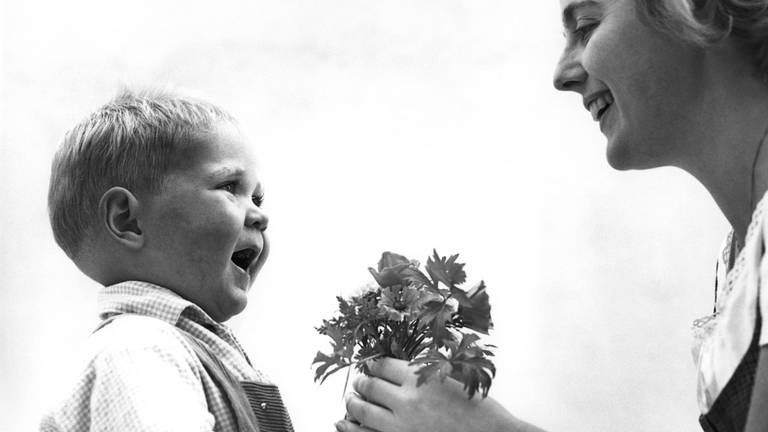 Kleiner junge überreicht Blumen zum Muttertag (1960er-Jahre)