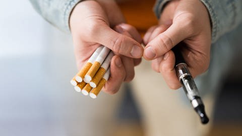 Zigaretten in einer Hand, in der anderen eine E-Zigarette, tags: Aromastoffe, Deutsche Gesellschaft für Pneumologie
