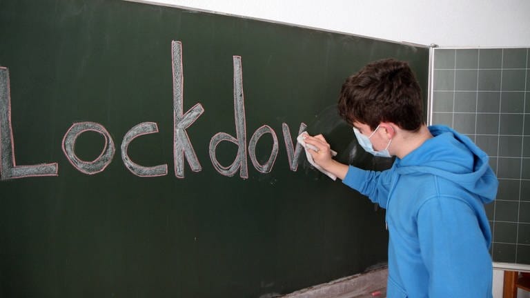Schüler wischt "Lockdown"-Aufschrift von Tafel