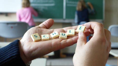 Schule: Hand mit Scrabble Buchstaben
