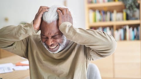 Älterer Mann mit schmerzverzerrtem Gesicht hält sich die Hände an den Kopf. (Foto: IMAGO, IMAGO / PhotoAlto)