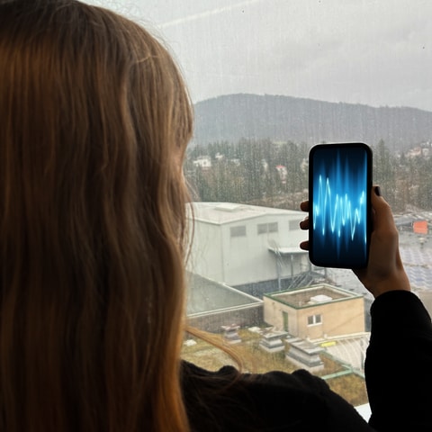 Eine Frau hält ein Handy in der Hand, auf dem eine Audiowelle zu erkennen ist.  (Foto: SWR)