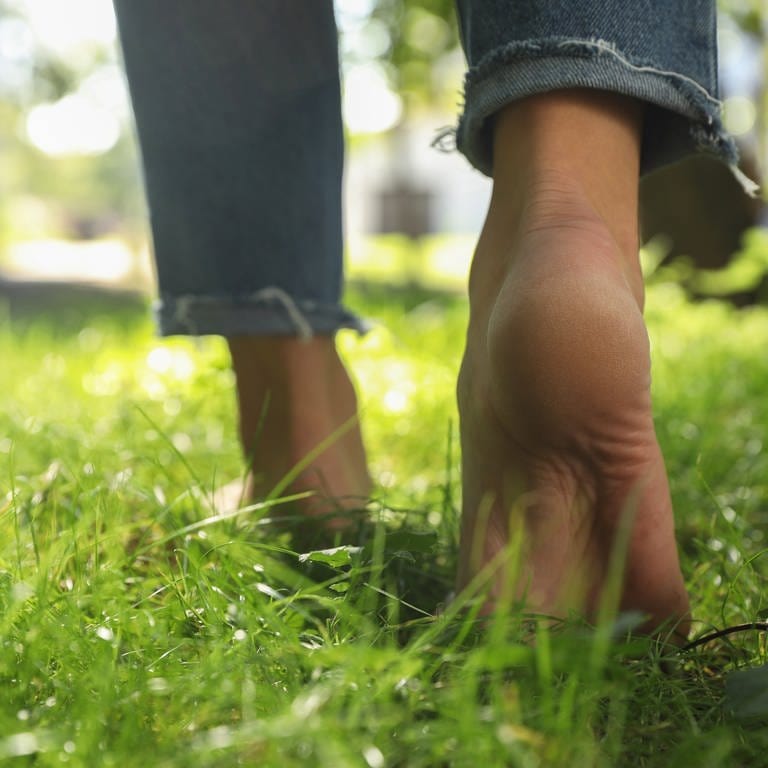 TikTok-Trend: Auf Social Media berichten viele von immensen gesundheitlichen Vorteilen durch das Rückwärtslaufen | Füße laufen im Gras. (Foto: IMAGO, IMAGO / Pond5 Images)