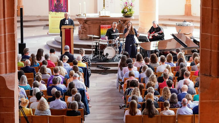 Sängerin Tine Wiechmann tritt in der Heiliggeistkirche während eines Taylor-Swift-Gottesdienstes auf. Links im Bild steht Pfarrer Vincenzo Petracca.