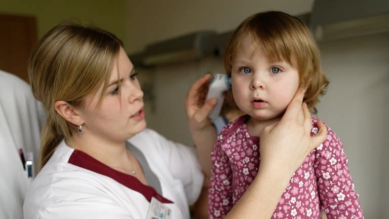 Krankenschwester misst bei einem Kleinkind die Temperatur. 