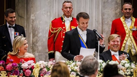 Während Präsident Macron eine Rede hält lachen Königin Máxima und König Willem-Alexander