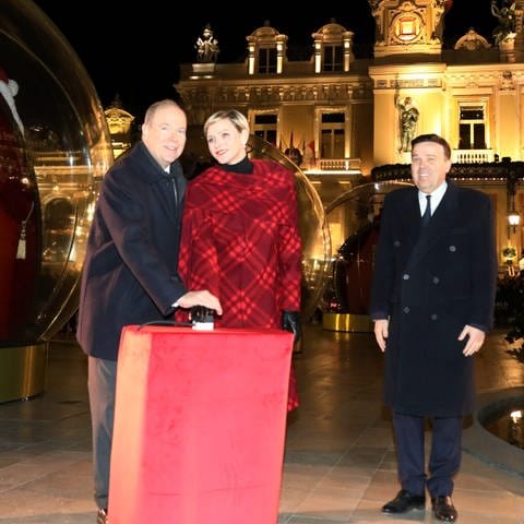 Mann und Frau stehen an einem Buzzer und legen eine Hand drauf - Fürst Albert und Charlène eröffnen Weihnachtsmarkt
