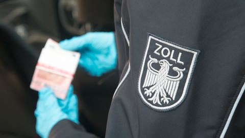 Ein Zollbeamter hat Geldscheine in der Hand - Bargeld darf nur bis zu einer Höhe von 10.000 Euro unangemeldet nach deutschland gebracht werden