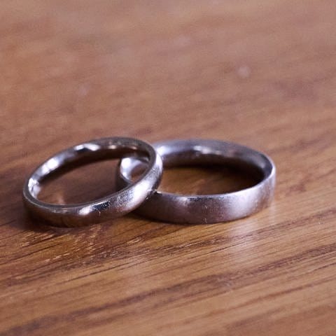 Zwei Eheringe auf einem Tisch: Heiratsschwindlerin aus Wiesbaden betrügt Mann um halbe Million Euro