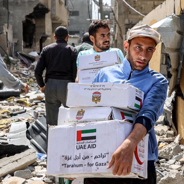 Palästinenser tragen Pakete mit Hilfslieferungen (Foto: AFP)