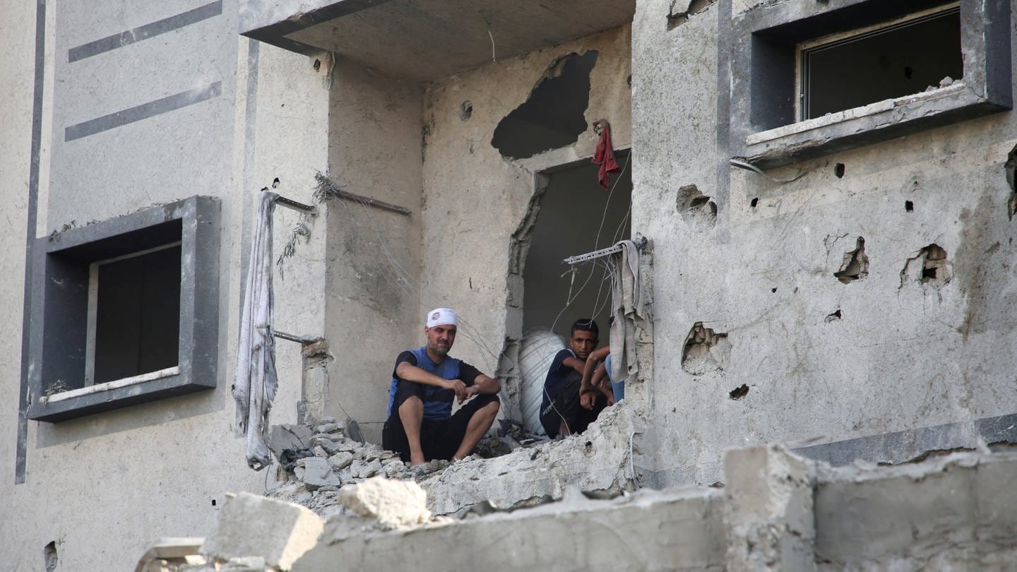Männer blicken aus einem schwer beschädigten Haus in Rafah (Foto: REUTERS)