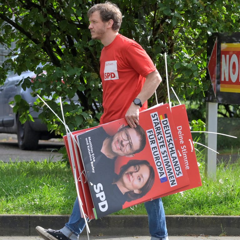 Ein Wahlhelfer trägt Plakate der SPD-Europakandidaten Matthias Ecke und Katarina Barley