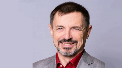 Ralf Scholl, Landesvorsitzender des Philologenverbands in Baden-Württemberg. Mann um die 50 mit schwarzen Haaren, grauem Musketierbart, rotem Hemd und grauem Sakko.  (Foto: SWR, Privat)