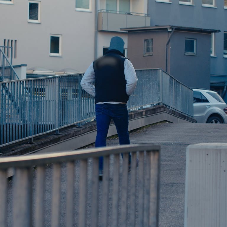Ein großer muskulöser Mann läuft die Straße entlang. Er ist anonymisiert dargestellt, weil er eine lange Zeit im rechtsradikalen Milieu aktiv war. (Foto: SWR)