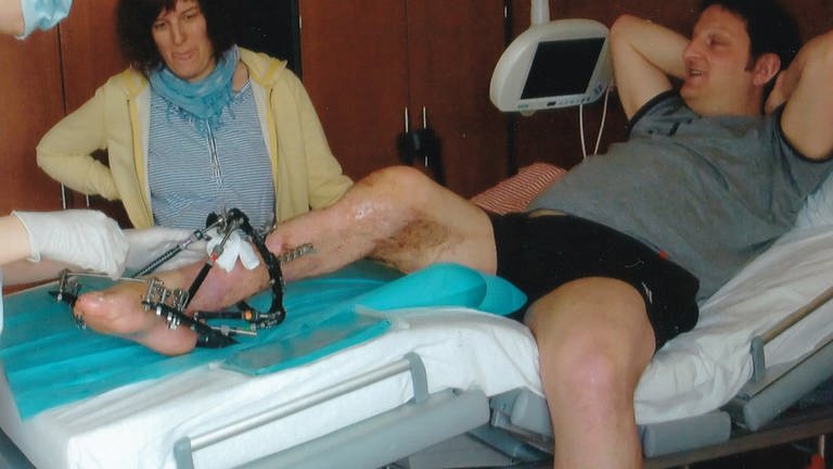 Fritz liegt in einem Krankenhauszimmer. Sein Bein sieht demoliert aus und ist mit Verbänden und Schienen eingewickelt.  (Foto: Keine)