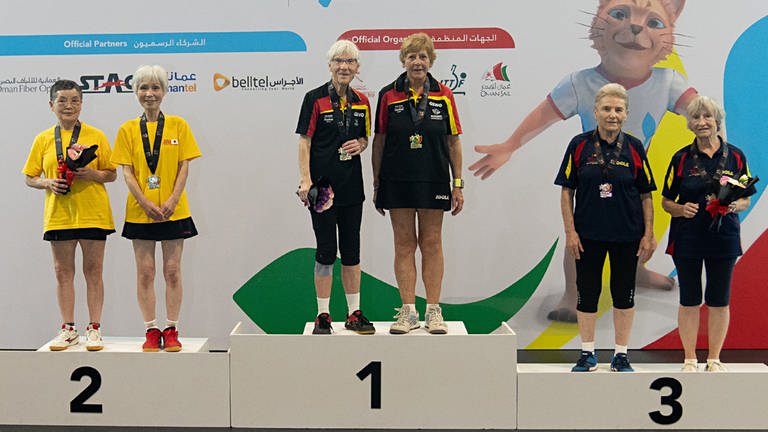 Gruppenbild des Siegertreppchen der Tischtennis-WM der Senioren im Doppel: Heidi steht mit Spielpartnerin auf dem ersten Podest, sie trägt eine goldene Medaille und hält einen Blumenstrauß. (Foto: SWR, ITTF/APAC Sport Media)