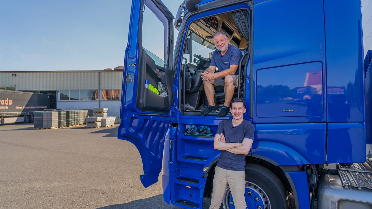 SWR Reporter Julian Camargo und LKW-Fahrer Andreas Selleng sitzen und stehen vor einem blauen LKW und lächeln in die Kamera (Foto: SWR)