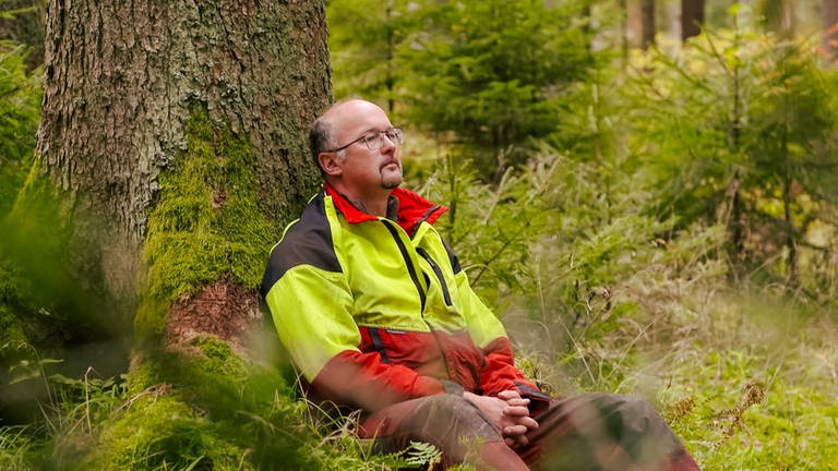 Mann lehnt im Wald an einem Baum (Foto: SWR)