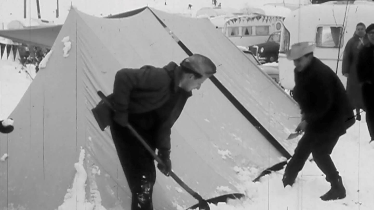 Zwei männlich gelesene Menschen schippen Schnee von einem Zelt (Foto: SWR)