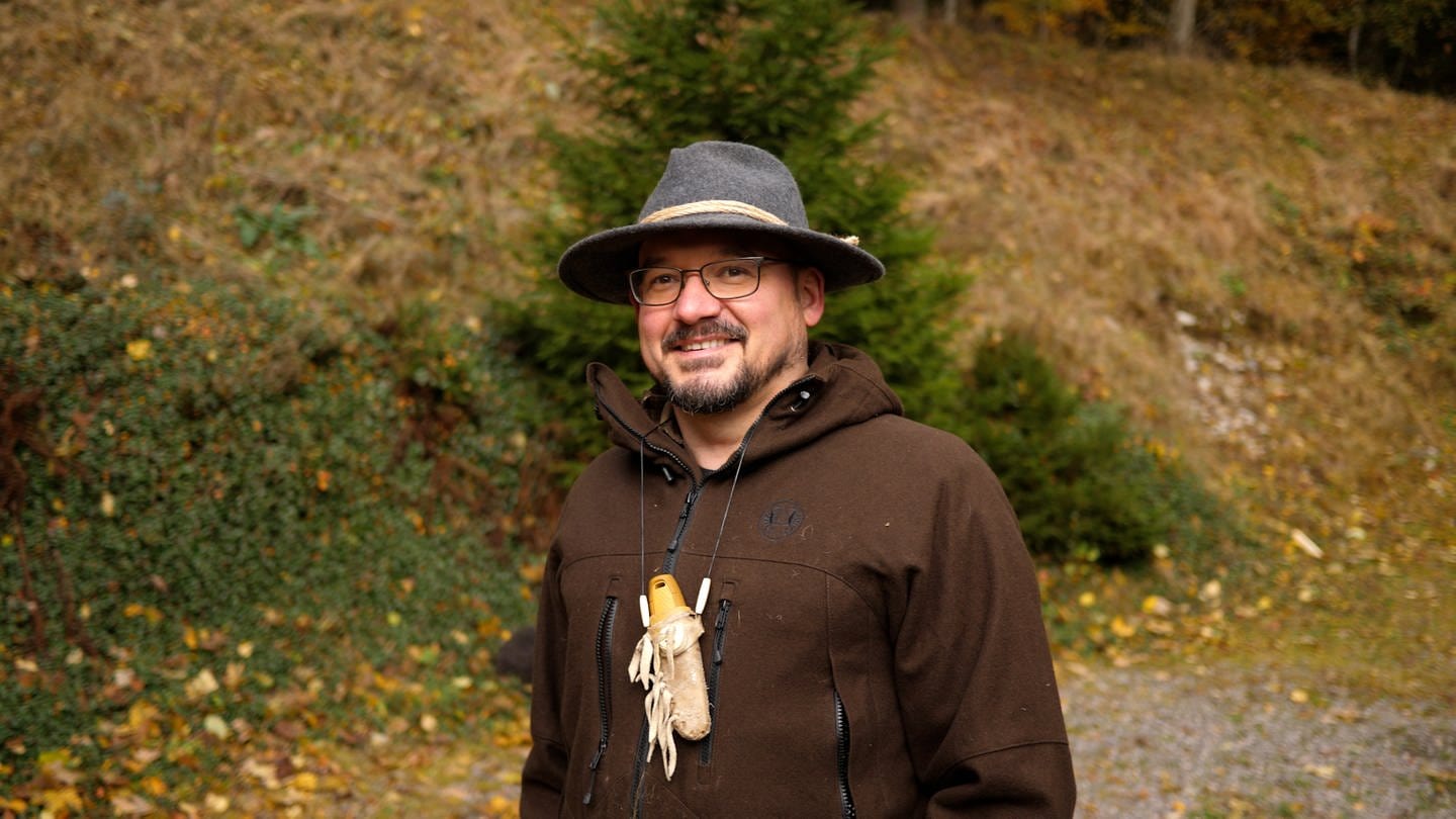 Der Survival Profi Ralf lächelt in die Kamera. Er steht mitten im Wald, sein Revier. (Foto: SWR)