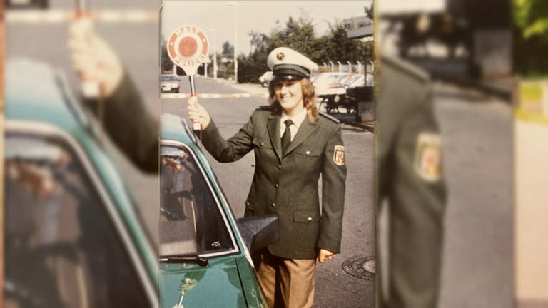 Die junge Claudia Müller steht in Uniform neben einem Streifenwagen und hält eine Polizeikelle. Sie war 1987 die erste Frau in Uniform bei der rheinland-pfälzischen Polizei. (Foto: SWR)