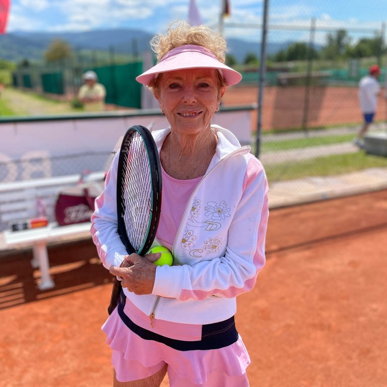 Seniorin steht auf dem Tennisplatz mit Schläger in der Hand