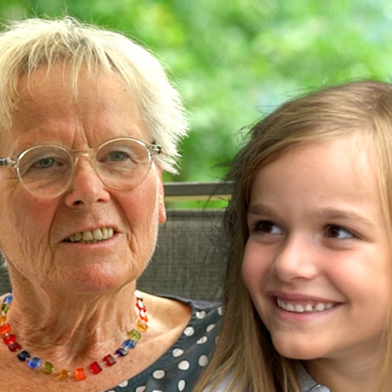 Eine ältere Dame und ein junges Mädchen lächeln in die Kamera