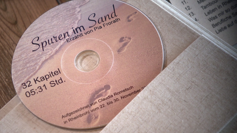 Eine CD mit einem Bild von Sand und Fußspuren.