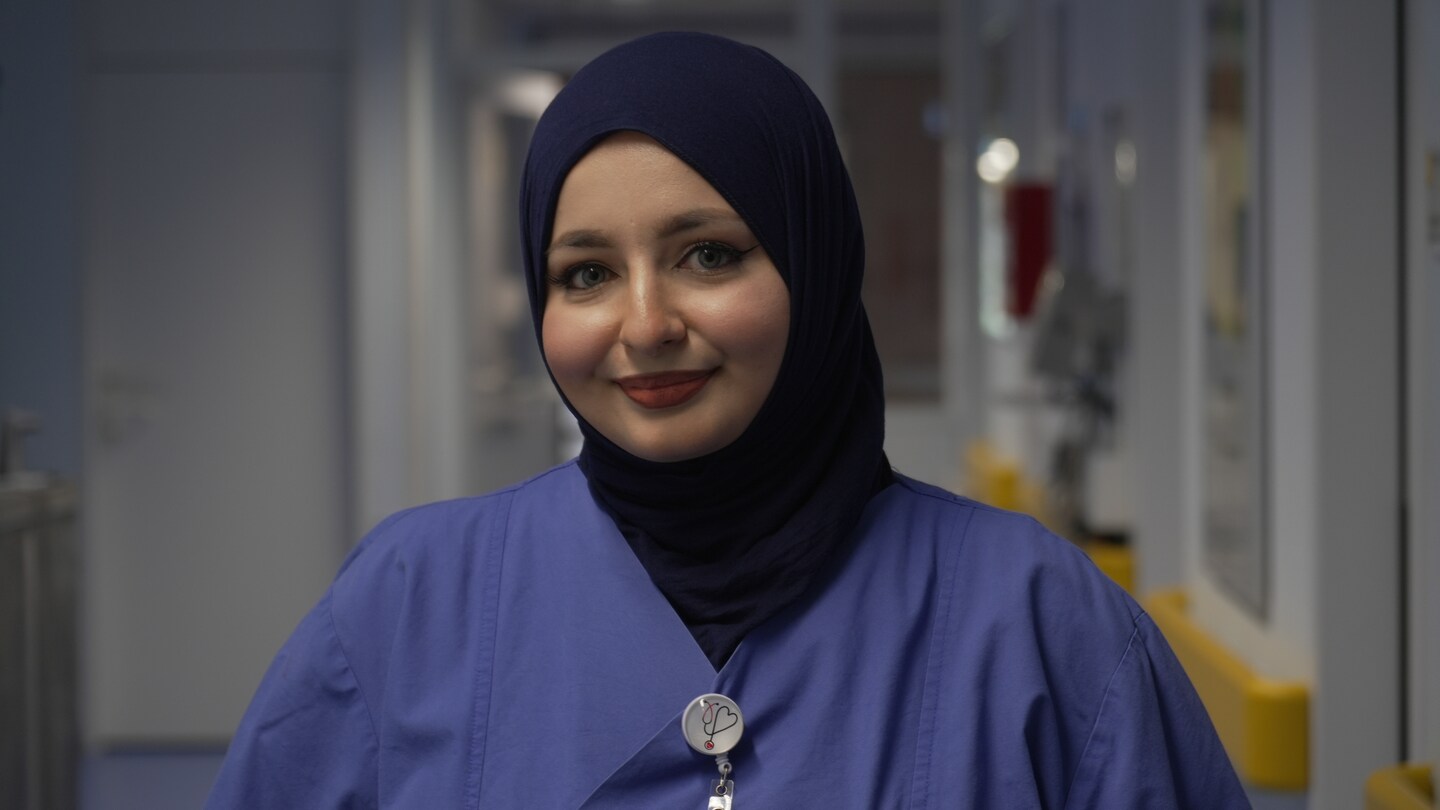 Eine Krankenpflegerin mit Kopftuch steht im Krankenhausflur und lächelt (Foto: SWR)