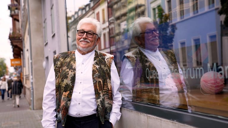 Älterer Mann mit weißem Haar steht vor Schaufenster